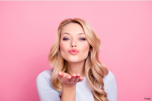 A photo of a blonde woman blowing a kiss.