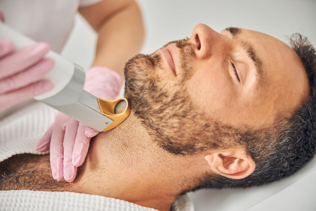 A photo of a man getting laser hair removal treatment on his neck.