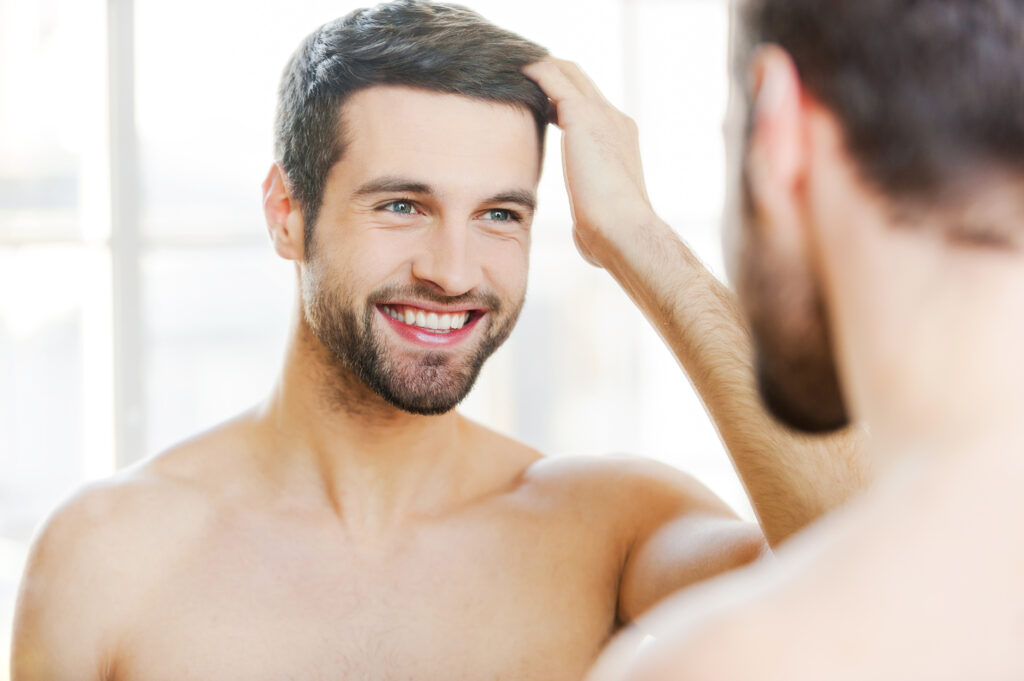 A photo of a man looking in a mirror.