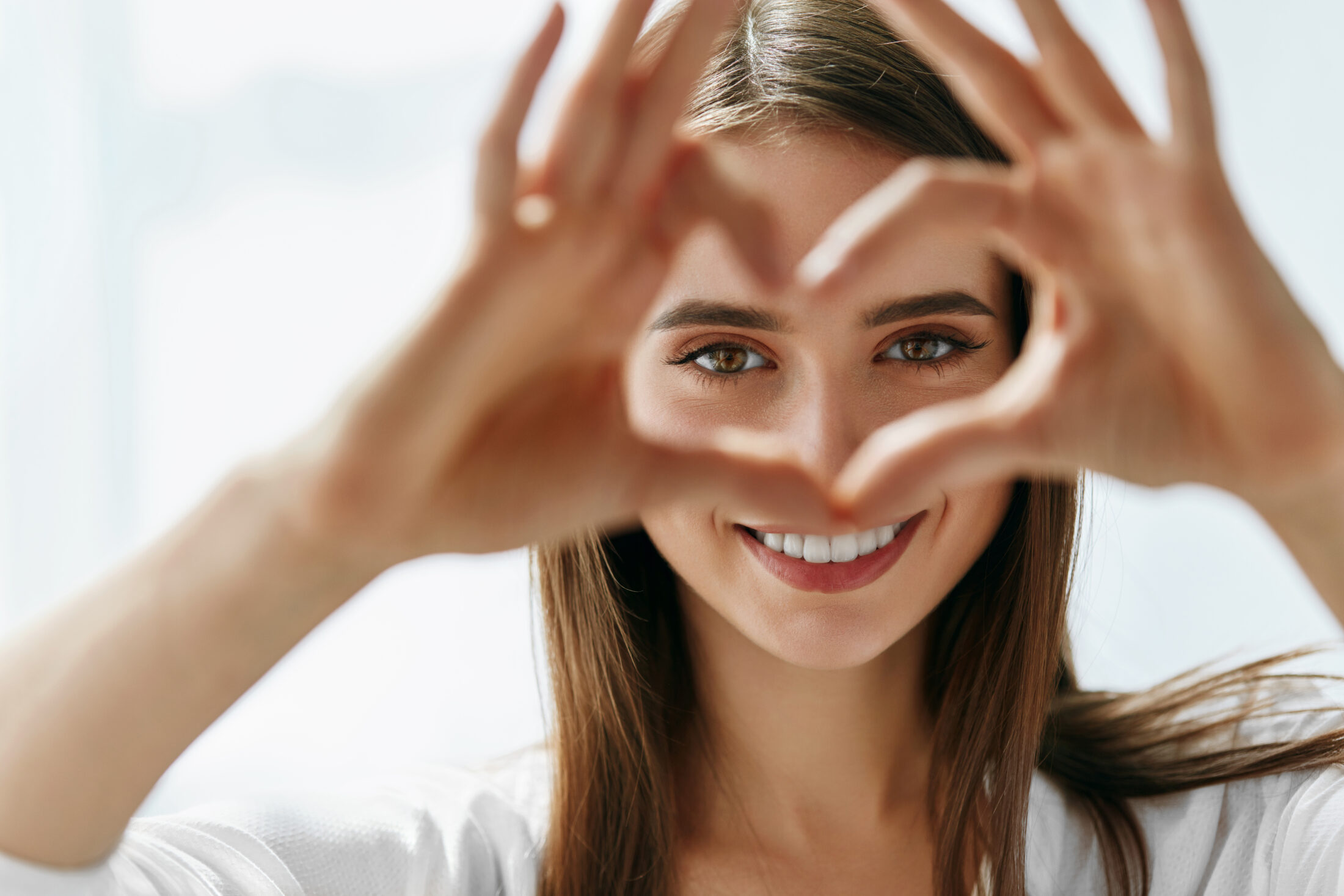 A photo of woman making a heart shape with her hands.